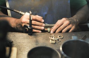 Jeweller repairing rings at a wooden bench