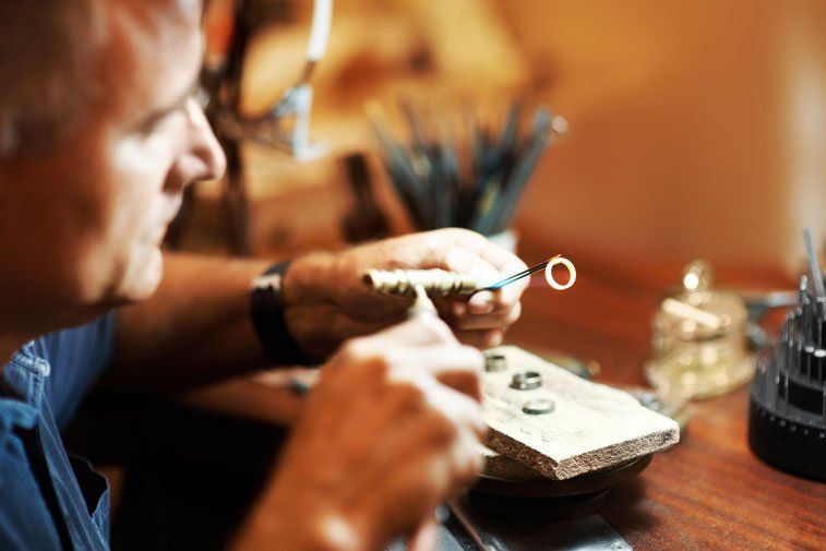 Jeweller heating a gold ring at the bench