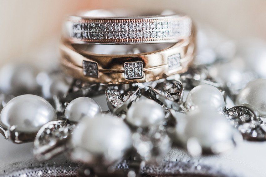 Wedding bands stacked above a pearl necklace